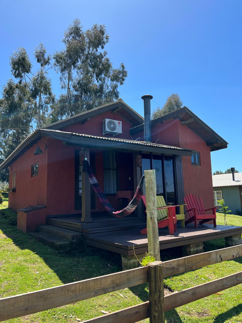 Cabana de madeira com varanda, deck, redes e cadeiras no gramado do Ninho da Coruja